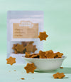 Star-shaped crackers in a bowl with a package labeled 'little tummy' on a light green background